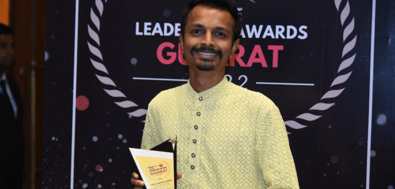 Founder of Jalark Solars, smiling and holding a trophy on stage with an awards banner in the background