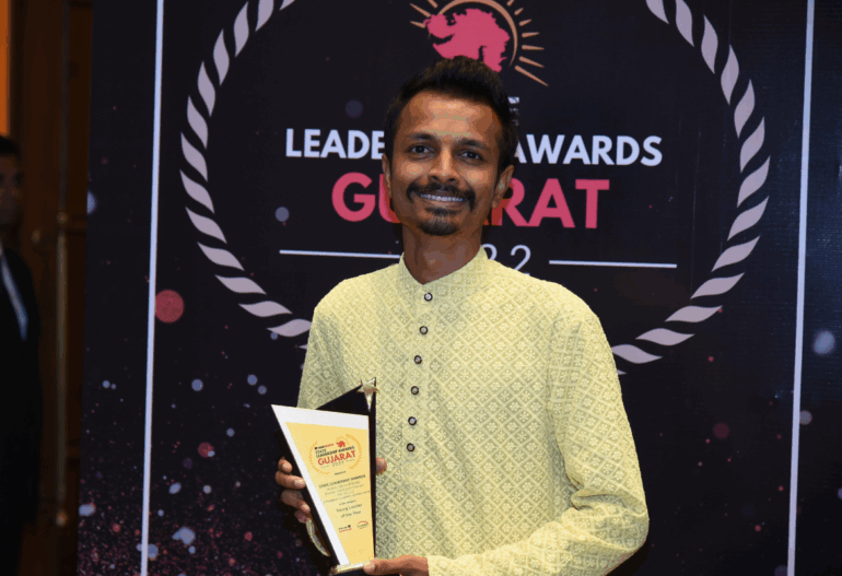 Founder of Jalark Solars, smiling and holding a trophy on stage with an awards banner in the background