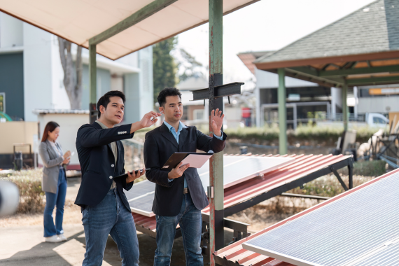 Two professionals discussing a solar project while standing outdoors near a small existing solar array.