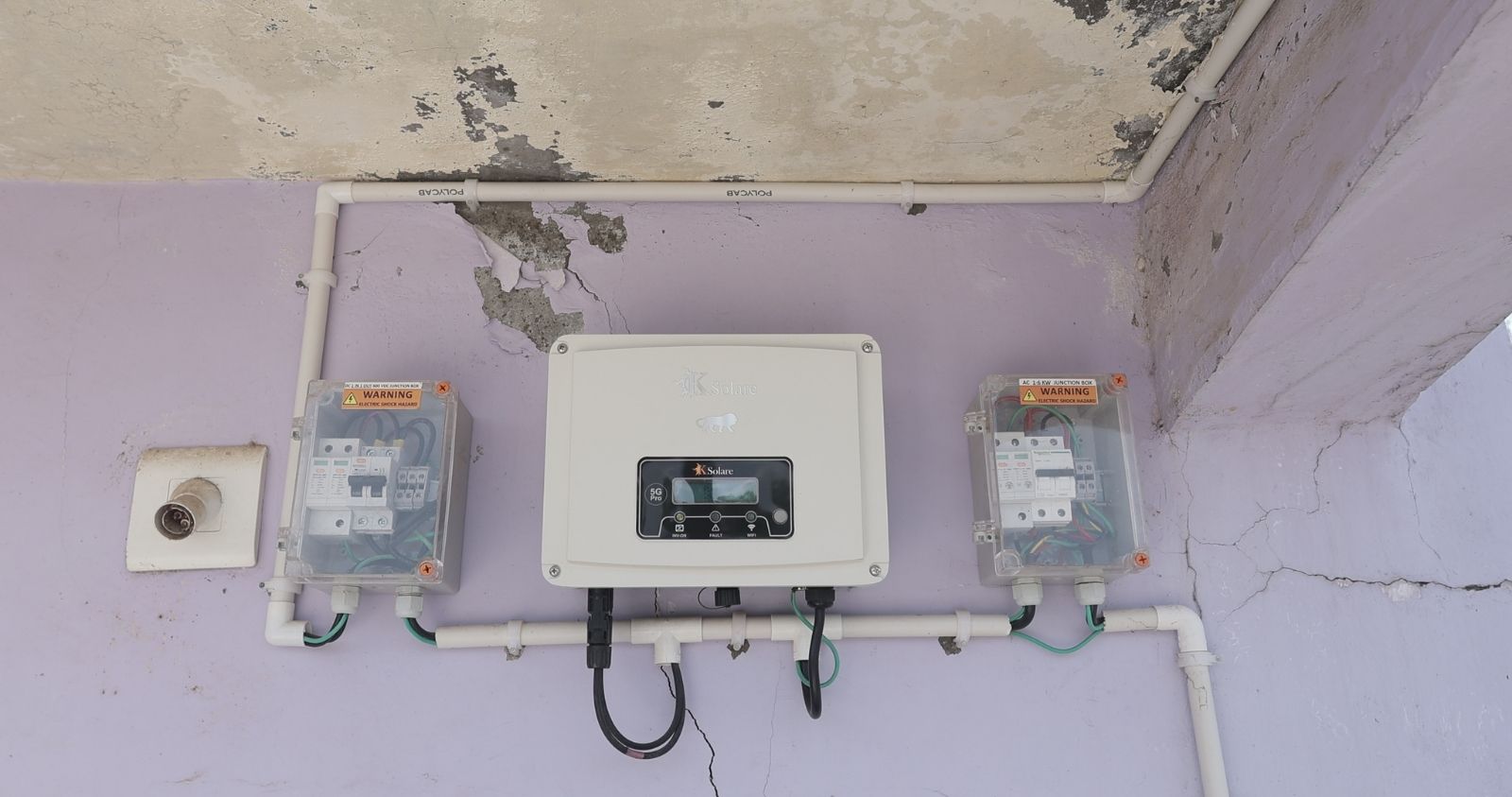 A power inverter and associated wiring mounted on an exterior wall between two electric meters.