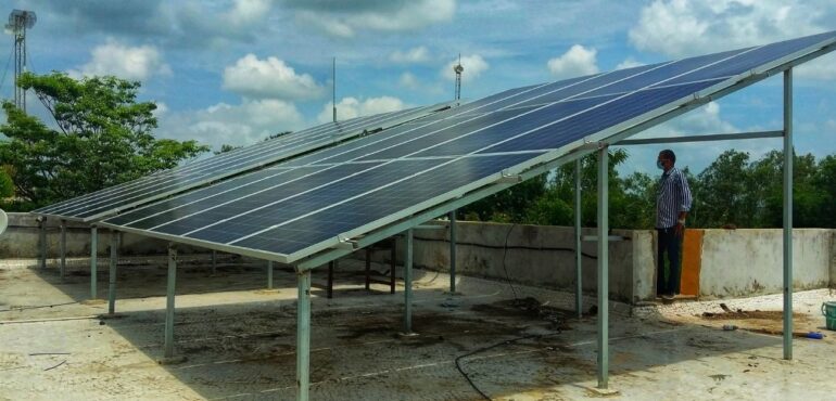 Elevated solar panels installed on a flat, concrete rooftop, with support structure clearly visible.