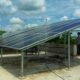 Elevated solar panels installed on a flat, concrete rooftop, with support structure clearly visible.
