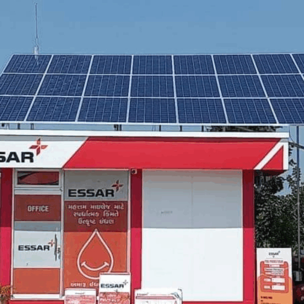 Solar panels installed over a red and white Essar office structure, with a blue sky background.