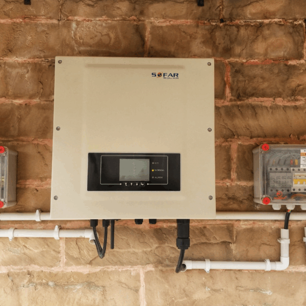 A central solar inverter mounted on a textured brick wall with visible wiring, likely for a commercial or large residential installation.